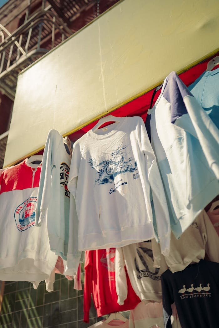 Brightly colored sweatshirts hanging at an outdoor market stall, showcasing casual fashion.